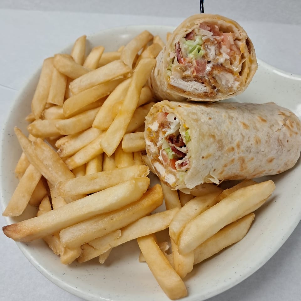 A Kalispell Kitchen breakfast burrito, cut in half, served with a side of golden french fries.